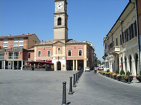 司教館（左の時計塔のある建物）。右奥に続く路地はエミリア・ロマーニャ街道。